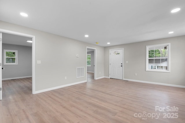 unfurnished living room with plenty of natural light, light wood-style flooring, baseboards, and recessed lighting
