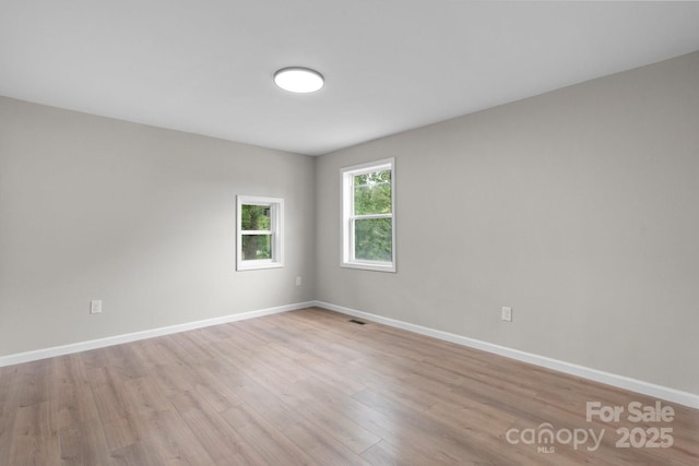 unfurnished room with light wood-style flooring and baseboards