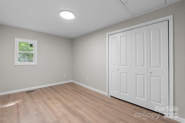 unfurnished bedroom with light wood finished floors, baseboards, and a closet