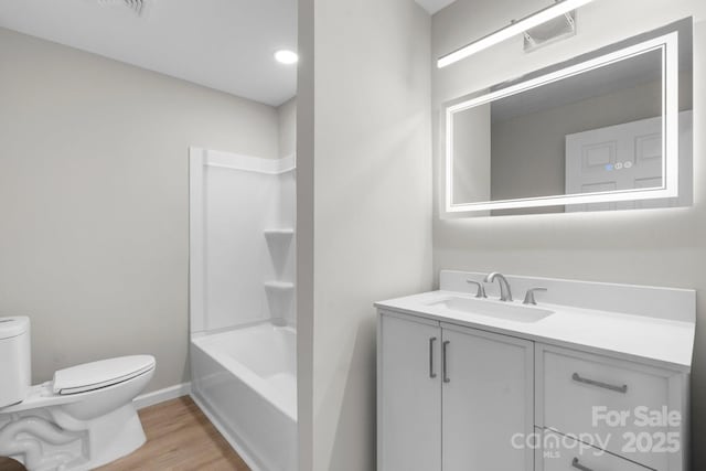 full bath featuring toilet, wood finished floors, vanity, baseboards, and shower / bathtub combination