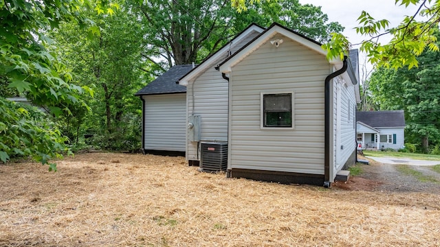 rear view of property with central AC unit and a shingled roof