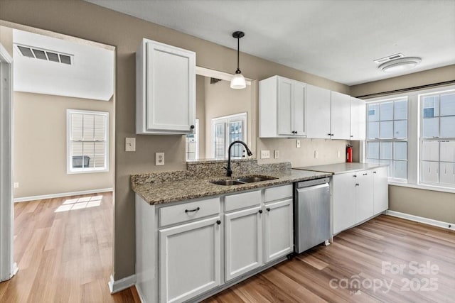 8610 Sawleaf Ct, Charlotte, NC 28215 - kitchen featuring a sink, dishwasher, light wood finished floors, baseboards, and white cabinets