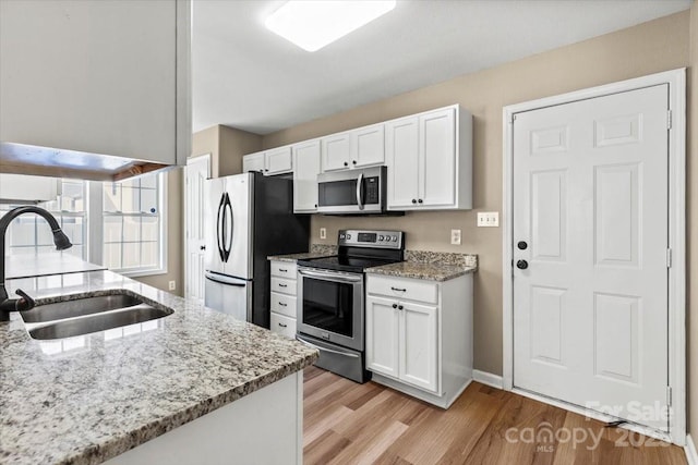8610 Sawleaf Ct, Charlotte, NC 28215 - kitchen with stainless steel appliances, a sink, light wood-style flooring, white cabinets, and light stone countertops