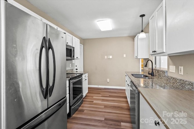 8610 Sawleaf Ct, Charlotte, NC 28215 - kitchen featuring appliances with stainless steel finishes, light wood finished floors, a sink, white cabinetry, and baseboards