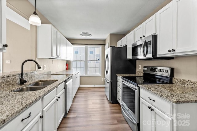 8610 Sawleaf Ct, Charlotte, NC 28215 - kitchen featuring stainless steel appliances, a sink, white cabinetry, wood finished floors, and light stone countertops