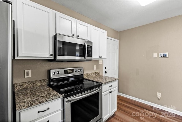 8610 Sawleaf Ct, Charlotte, NC 28215 - kitchen featuring appliances with stainless steel finishes, wood finished floors, baseboards, white cabinetry, and dark stone counters