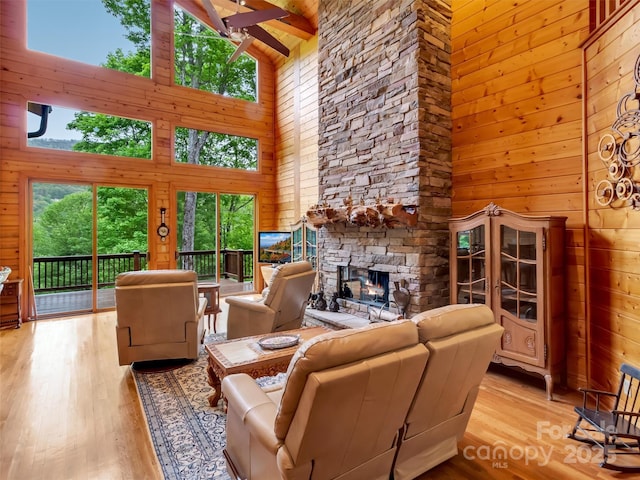 421 Ramp Patch Ln, Waynesville, NC 28786 - living area with high vaulted ceiling, wooden walls, a fireplace, light wood-style floors, and ceiling fan