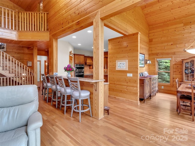 421 Ramp Patch Ln, Waynesville, NC 28786 - kitchen with wood walls, a breakfast bar area, light wood-style flooring, brown cabinets, and light countertops