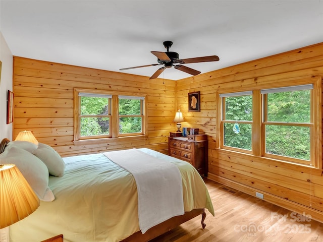 421 Ramp Patch Ln, Waynesville, NC 28786 - bedroom with multiple windows, light wood-style flooring, wooden walls, and ceiling fan