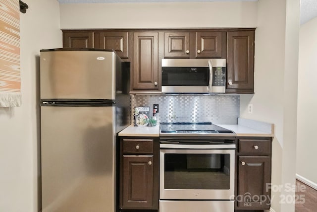 kitchen with appliances with stainless steel finishes, dark brown cabinets, light countertops, and backsplash