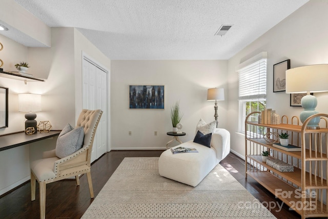 sitting room featuring a textured ceiling, baseboards, dark wood finished floors, and a desk