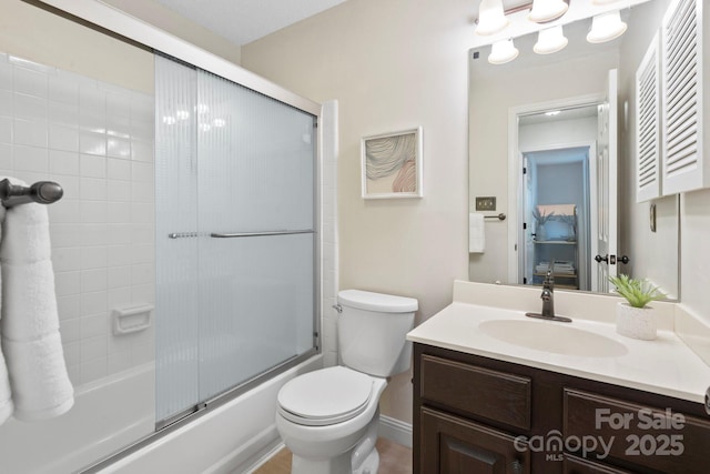 full bath featuring toilet, vanity, and bath / shower combo with glass door