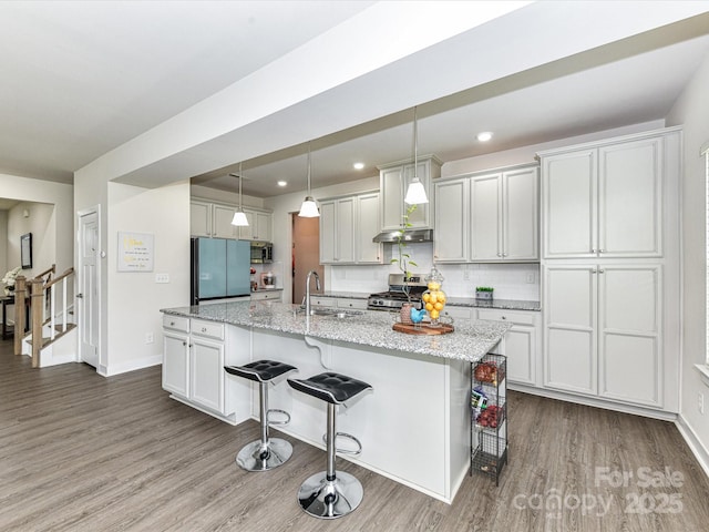 3023 Ballester Rd, Fort Mill, SC 29707 - kitchen featuring stainless steel appliances, a sink, wood finished floors, a kitchen breakfast bar, and under cabinet range hood