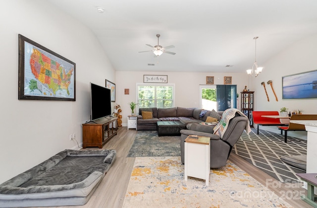 living area featuring lofted ceiling, wood finished floors, a chandelier, and ceiling fan