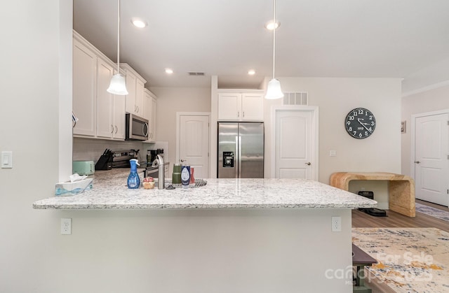 kitchen featuring stainless steel appliances, a peninsula, backsplash, wood finished floors, and pendant lighting