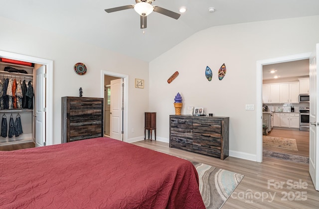 bedroom featuring vaulted ceiling, light wood-style floors, baseboards, a walk in closet, and ceiling fan