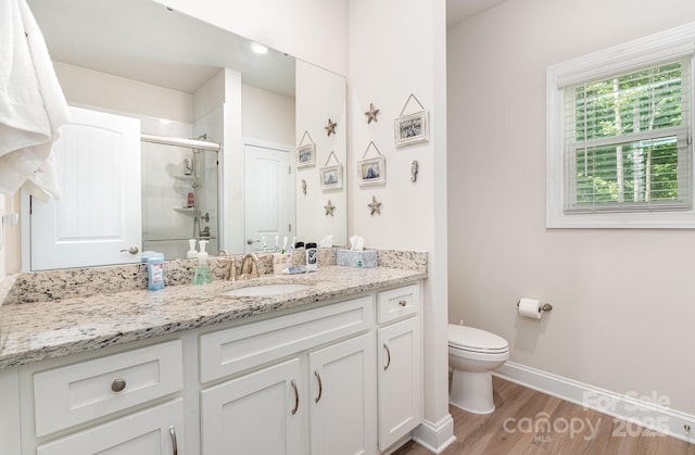 full bathroom with a shower stall, toilet, baseboards, wood finished floors, and vanity