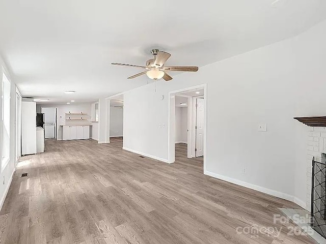 10379 Turnplow Dr, Davidson, NC 28036 - unfurnished living room featuring a ceiling fan, light wood finished floors, baseboards, and a fireplace