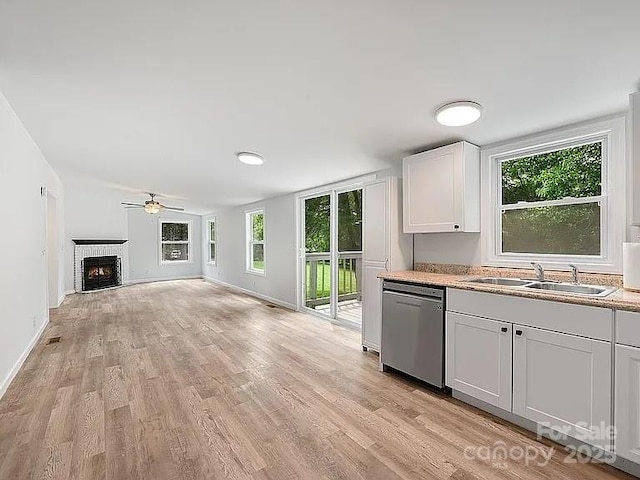 10379 Turnplow Dr, Davidson, NC 28036 - kitchen with dishwasher, a brick fireplace, ceiling fan, light wood finished floors, and baseboards