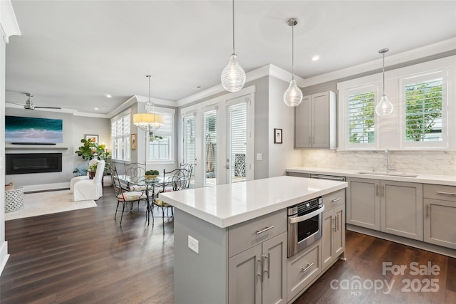 7908 Rea View Ct, Charlotte, NC 28226 - kitchen featuring a sink, gray cabinets, a glass covered fireplace, open floor plan, and ornamental molding