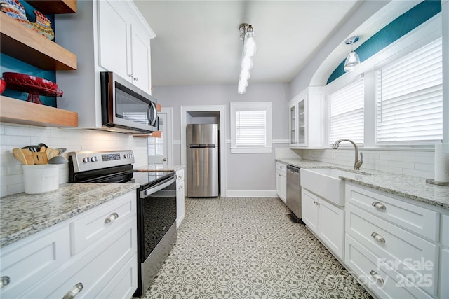 501 Pee Dee Ave, Albemarle, NC 28001 - kitchen with appliances with stainless steel finishes, open shelves, a sink, baseboards, and backsplash