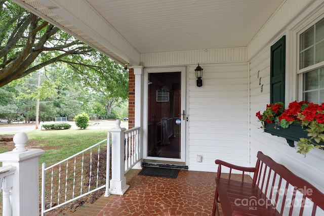 property entrance featuring covered porch and a yard