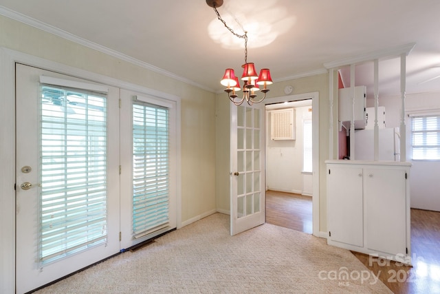 unfurnished dining area featuring a chandelier, ornamental molding, french doors, carpet, and baseboards