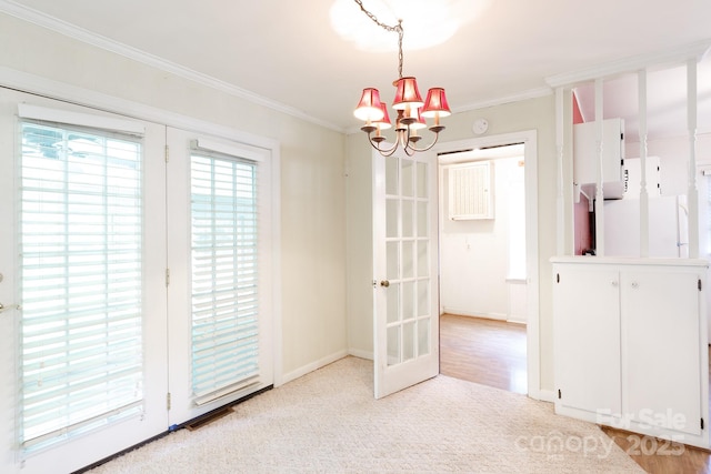 unfurnished dining area featuring a chandelier, crown molding, french doors, light carpet, and baseboards