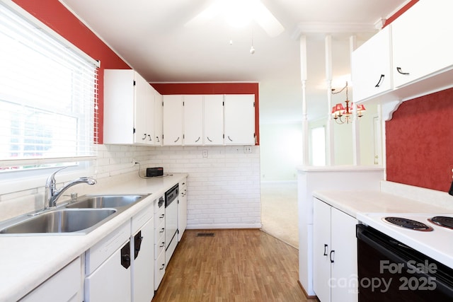 kitchen with electric range, a sink, white dishwasher, white cabinets, and light countertops