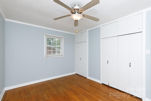 unfurnished bedroom with ornamental molding, wood finished floors, baseboards, and ceiling fan