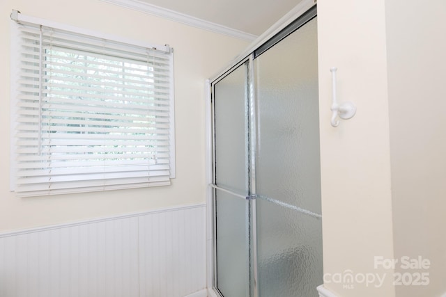 bathroom with an enclosed shower, ornamental molding, and a wainscoted wall
