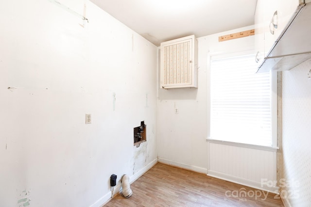 clothes washing area featuring light wood finished floors and baseboards