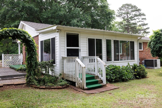 rear view of property with a yard, a wooden deck, and central AC
