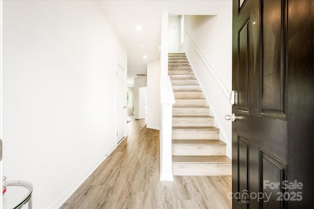 stairs with wood finished floors, recessed lighting, and baseboards