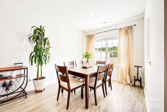 dining space with light wood finished floors and baseboards