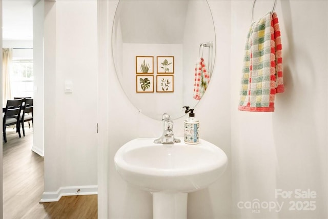 bathroom featuring baseboards, wood finished floors, and a sink