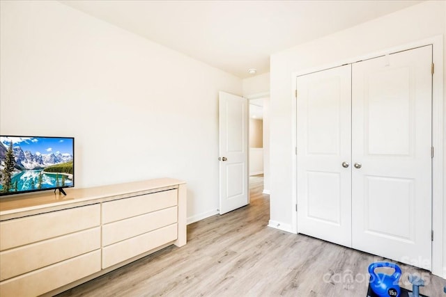 unfurnished bedroom with light wood-style floors, baseboards, and a closet