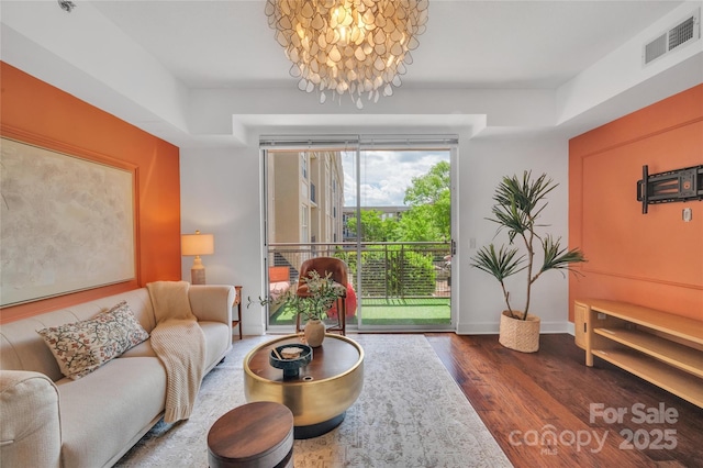 living room with dark wood-style flooring, a chandelier, and baseboards
