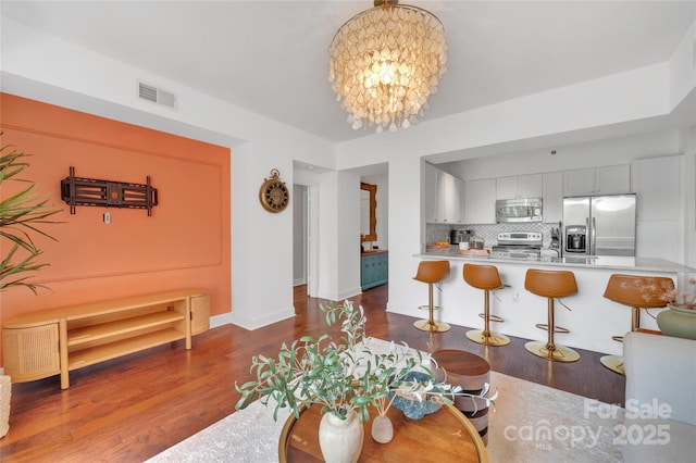 living area featuring dark wood-style flooring, a chandelier, and baseboards