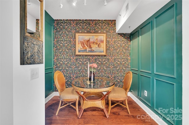 dining room featuring wallpapered walls, wood finished floors, and baseboards