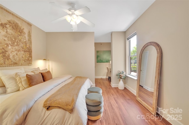 bedroom with light wood finished floors, baseboards, and a ceiling fan