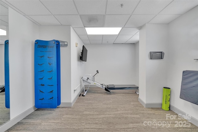exercise room with a drop ceiling, wood finished floors, and baseboards
