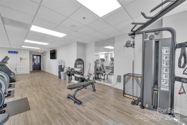 workout area featuring wood finished floors, a paneled ceiling, and baseboards