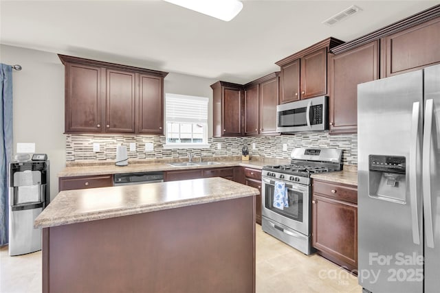 12217 Dearview Ln, Charlotte, NC 28269 - kitchen with stainless steel appliances, a sink, decorative backsplash, a center island, and light countertops