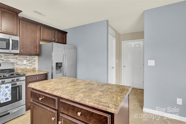 12217 Dearview Ln, Charlotte, NC 28269 - kitchen with appliances with stainless steel finishes, backsplash, a kitchen island, dark brown cabinetry, and light tile patterned flooring