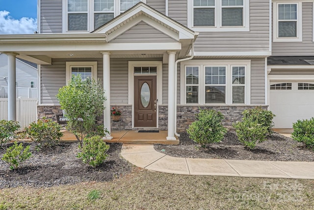entrance to property with stone siding, an attached garage, and covered porch