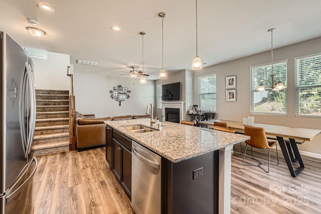 kitchen with appliances with stainless steel finishes, a sink, open floor plan, light wood-style flooring, and recessed lighting