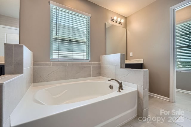 full bath featuring a bath, vanity, baseboards, and tile patterned flooring