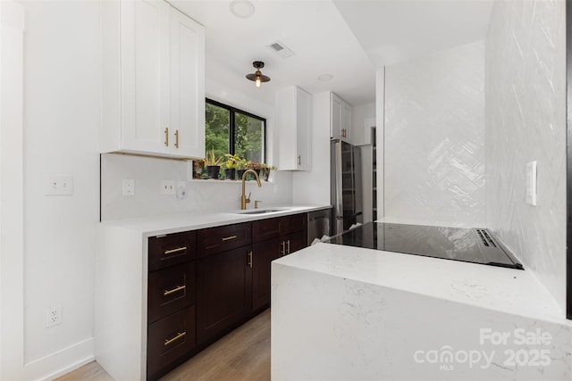 6824 Cortez Trl, Charlotte, NC 28227 - kitchen featuring a sink, white cabinets, stainless steel appliances, dark brown cabinets, and light wood finished floors