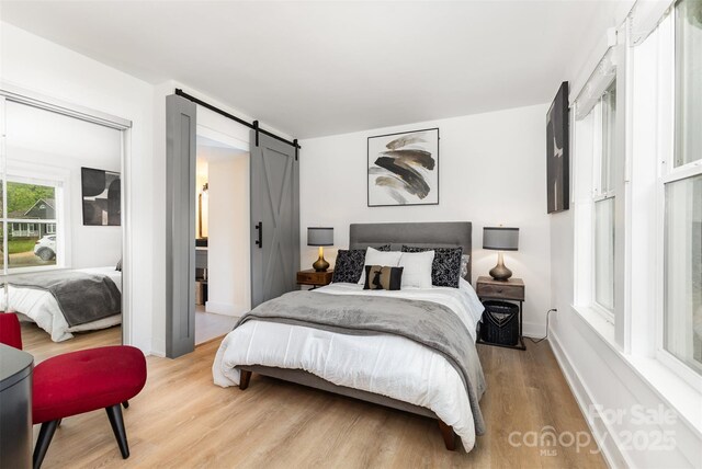 6824 Cortez Trl, Charlotte, NC 28227 - bedroom featuring light wood-style floors, a barn door, and baseboards
